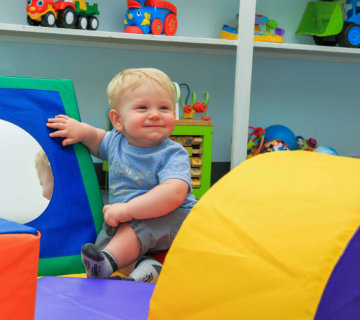 Toddler climbing through the soft play area